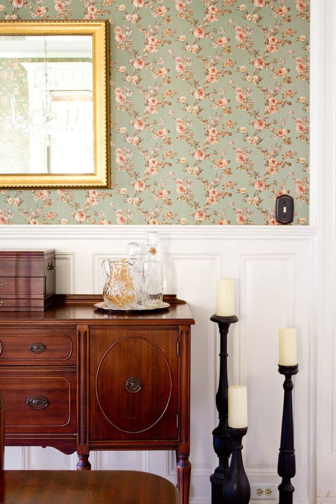 Dining room with green floral wallpaper, a wood accent cabinet, and elegant candle holders